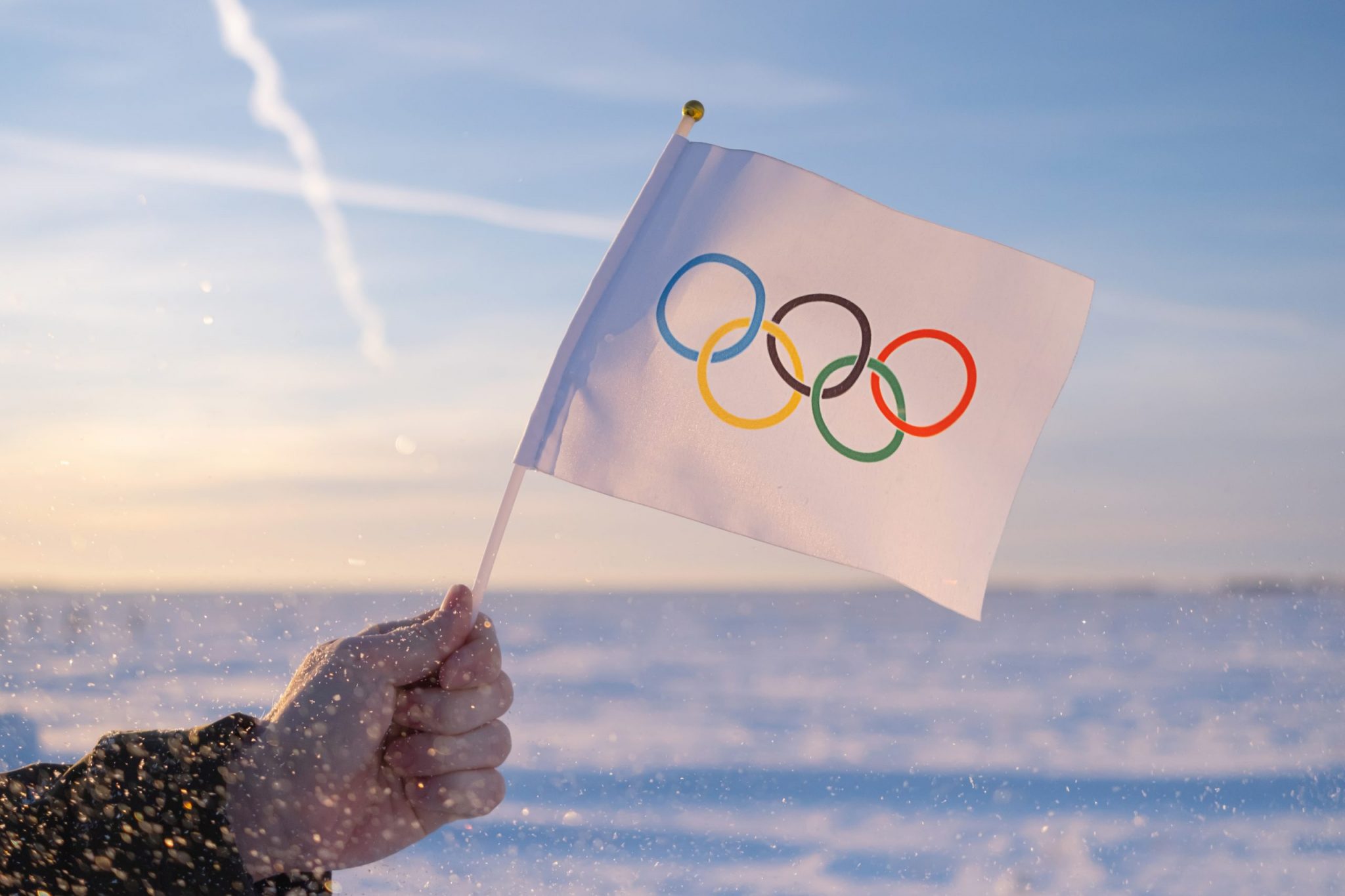 Beijing, China - 10.10.2021 - The Olympic flag, small in hand, flutters against the backdrop of snow and trees Concept for Winter Olympic Games 2022.