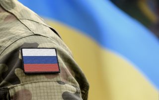 Flag of Russia on military uniform and flag of the Ukraine at background. Russia VS Ukraine.